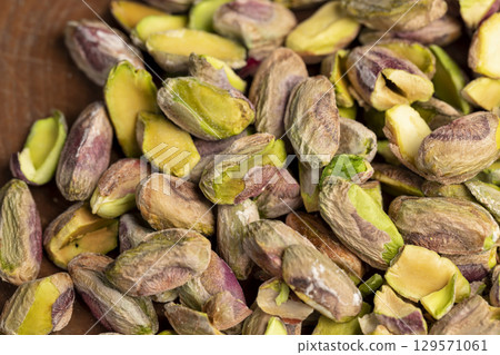 pistachios chopped and crushed into pieces of different sizes, a bunch of green crunchy pistachios, closeup 129571061