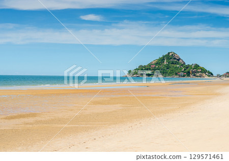 Tranquil beach with an island view under blue skies 129571461