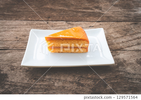 Slice of Thai tea cake on a white plate Slice of Thai tea cake on a white plate 129571564
