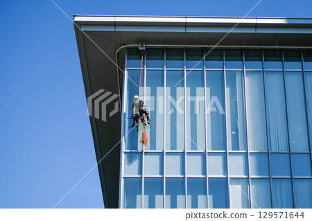 Window cleaner on high-rise building exterior Window cleaner on high-rise building exterior 129571644