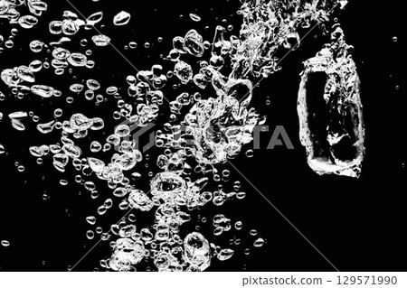 A lot of air bubbles flying into the water on a black background. A lot of air bubbles flying into the water on a black background. 129571990