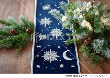 Christmas table runner with snowflakes, moon and stars decorating a wooden table 129572613