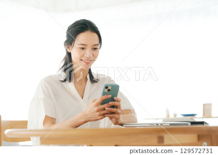 A woman using a smartphone in the living room 129572731