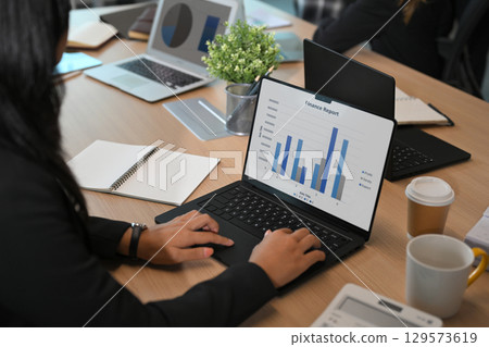 Businesswoman analyzing finance report on laptop during a corporate meeting in modern office Businesswoman analyzing finance report on laptop during a corporate meeting in modern office 129573619