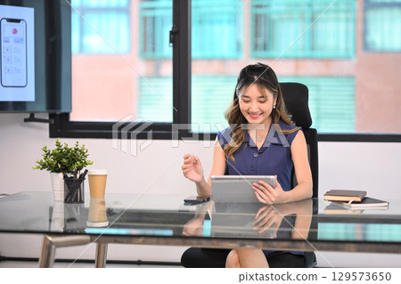 Young businesswoman working on a tablet during a productive morning in a modern office Young businesswoman working on a tablet during a productive morning in a modern office 129573650