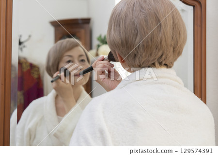 老年婦女在鏡子前化妝 129574391
