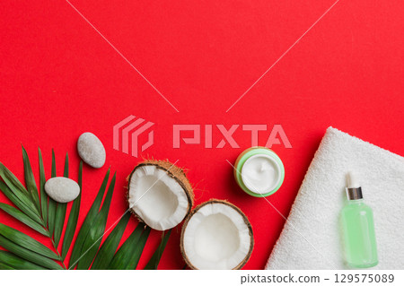 Coconut with jars of coconut oil and cosmetic cream on colored background. Top view. Free space for your text. Natural spa coconut cosmetics and organic treatment concept Coconut Spa composition Coconut with jars of coconut oil and cosmetic cream on colored background. Top view. Free space for your text. Natural spa coconut cosmetics and organic treatment concept Coconut Spa composition 129575089
