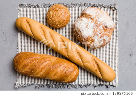 Assortment of freshly baked bread with napkin on rustic table top view. Healthy unleavened bread. French bread 129575106
