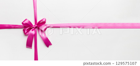 Top view of purple ribbon rolled and pink bow isolated on colored background. Flat lay with copy space Top view of purple ribbon rolled and pink bow isolated on colored background. Flat lay with copy space 129575107