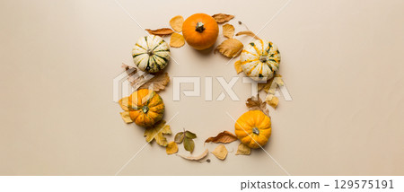 Autumn composition Pumpkins with fall leaves over coloredbackground. Top view with copy space 129575191