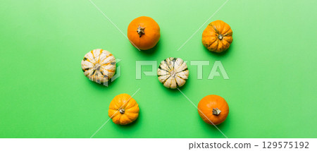 Autumn composition of little orange pumpkins on colored table background. Fall, Halloween and Thanksgiving concept. Autumn flat lay photography. Top view vith copy space 129575192