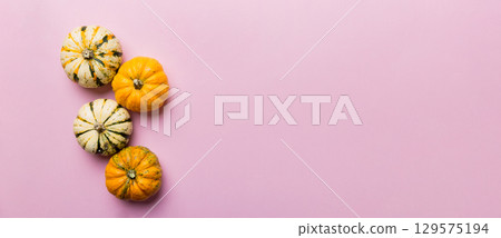 Autumn composition of little orange pumpkins on colored table background. Fall, Halloween and Thanksgiving concept. Autumn flat lay photography. Top view vith copy space Autumn composition of little orange pumpkins on colored table background. Fall, Halloween and Thanksgiving concept. Autumn flat lay photography. Top view vith copy space 129575194