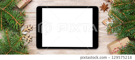 Digital tablet mock up with rustic Christmas wood background decorations for app presentation. top view with copy space 129575218