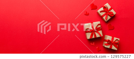 Valentine day composition: red gift box with bow and heart. Christmas present. View from above. Space for text. Holday greeting card Valentine day composition: red gift box with bow and heart. Christmas present. View from above. Space for text. Holday greeting card 129575227