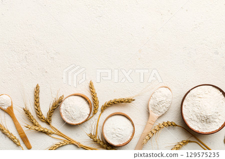 Flat lay of Wheat flour in wooden bowl with wheat spikelets on colored background. world wheat crisis 129575235