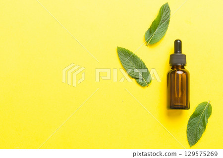 Natural Mint Essential Oil in a Glass Bottle. organic cosmetics with herbal extracts of mint on colored background Natural Mint Essential Oil in a Glass Bottle. organic cosmetics with herbal extracts of mint on colored background 129575269