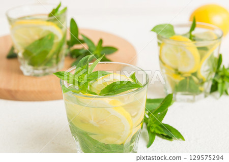 Mojito cocktail. Refreshing mojito cocktail with lime, lemon and mint in a tall glass with a stick Mojito cocktail. Refreshing mojito cocktail with lime, lemon and mint in a tall glass with a stick 129575294