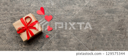 Valentine day composition: red gift box with bow and heart. Christmas present. View from above. Space for text. Holday greeting card 129575344