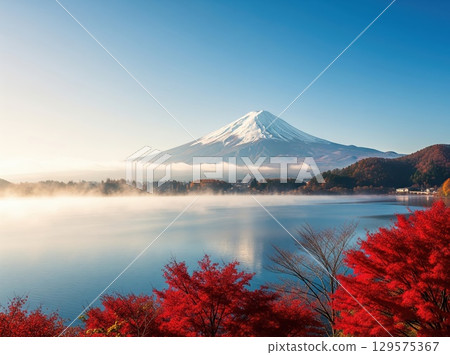 Radiant autumn colors highlight mountain behind fog as clear water reflects peaceful beauty of the season with vivid trees around Radiant autumn colors highlight mountain behind fog as clear water reflects peaceful beauty of the season with vivid trees around 129575367