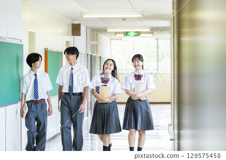 Male and female high school students walking down the school corridor Male and female high school students walking down the school corridor 129575458