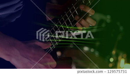 Image of glowing green light trails over mid section of caucasian man playing guitar Image of glowing green light trails over mid section of caucasian man playing guitar 129575731