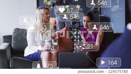 Image of social media icons and numbers over diverse businesswomen 129575780