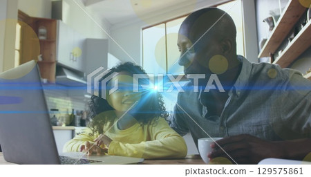 Image of light spots and trails over african american man and his daughter using laptop together 129575861
