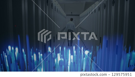 Image of glowing blue light trails over rear view of male engineer walking in server room 129575951