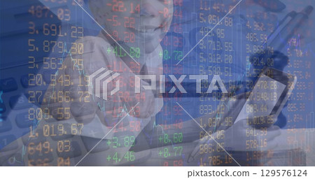 Pointing boy pressing stock market overlay at desk, with digital calculator numeric pad silver pen 129576124