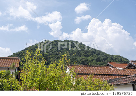 Mount Utsubuki and the red-tiled streets of Kurayoshi City's white-walled storehouses under the summer sky 129576725
