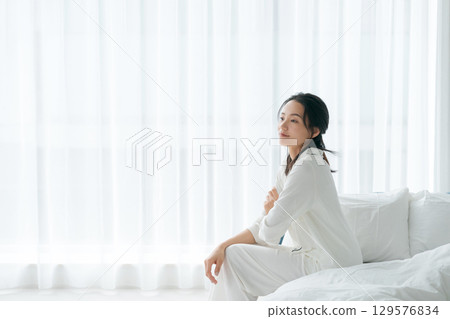 一位穿著睡衣的女士早上醒來坐在床上 129576834