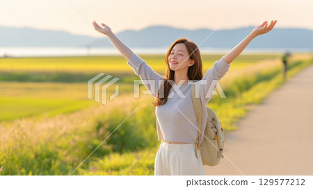 A woman spreading her arms out to the blue sky in a wide mountain grassland 129577212