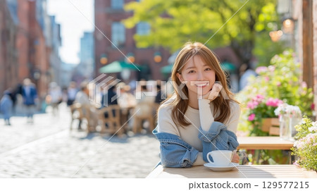 A woman relaxing on an open cafe terrace on a European street corner 129577215