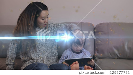 Image of light moving over happy asian mother and son with tablet sitting on sofa Image of light moving over happy asian mother and son with tablet sitting on sofa 129577751