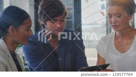 Image of data processing over diverse colleagues discussing over digital tablet at office 129577764