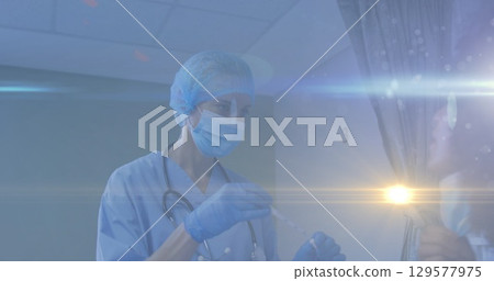 Image of light spot and light trails over female health workers working at hospital 129577975
