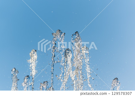 Splashes and jets of water against light background. Splashes and jets of water against light background. 129578307
