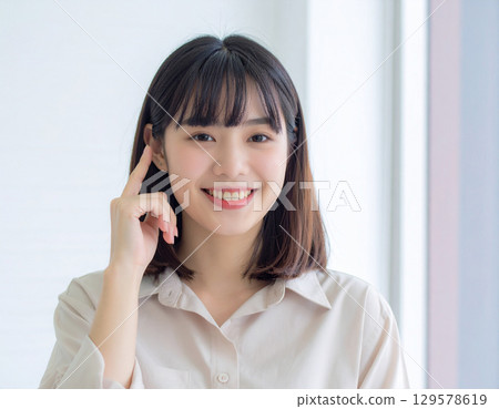 微笑的年輕女士將手指放在太陽穴上 129578619