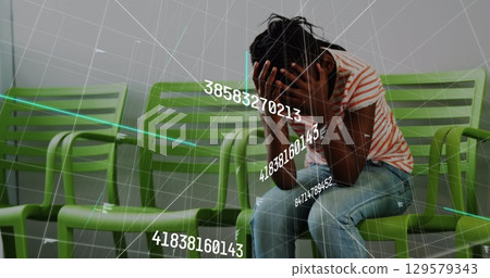 Image of numbers over sad african american woman in waiting room 129579343