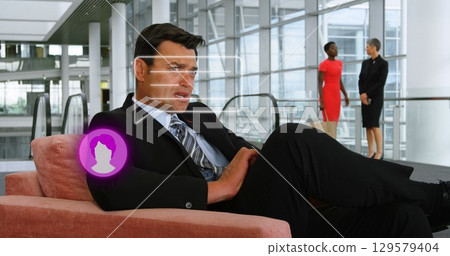 Image of person icon and speech bubble over caucasian businessman using smartphone in foyer Image of person icon and speech bubble over caucasian businessman using smartphone in foyer 129579404