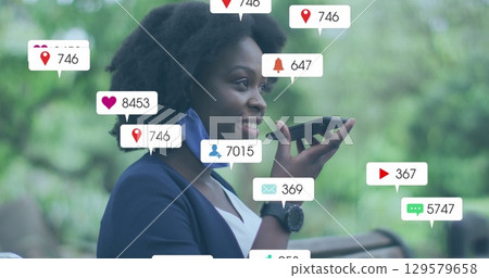 Image of social media icons with growing numbers over african american woman using smartphone 129579658