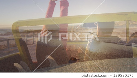 Image of light over happy caucasian couple in car on beach 129580175