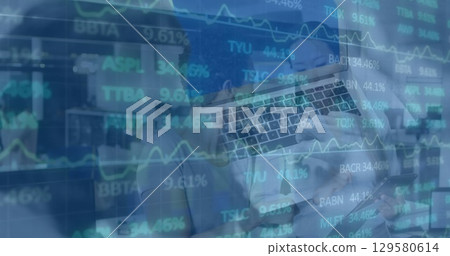 Two executives wearing blouse and blazer reviewing stock charts using laptop, smartphone in office Two executives wearing blouse and blazer reviewing stock charts using laptop, smartphone in office 129580614