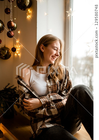 Woman Enjoying Cozy Winter Moments by the Window 129580748