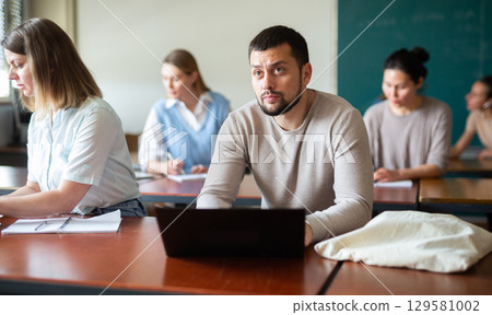 Bearded man university student sitting at table and using laptop 129581002