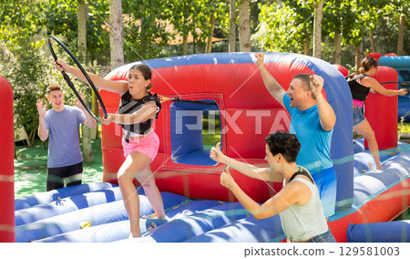 Girl reaching with hoop during competitive tug of war game 129581003