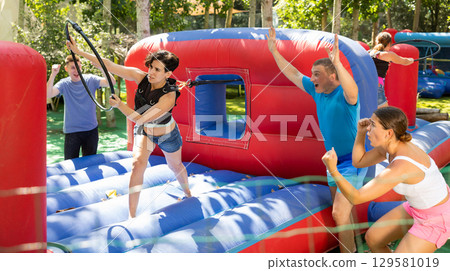 Woman playing tug of war game with hoop on playground in amusement park 129581019