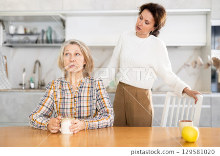 Offended elderly woman listens to complaints from her daughter at home Offended elderly woman listens to complaints from her daughter at home 129581020
