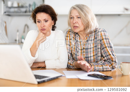 Old and middle-aged women speaking sadly by video-call using laptop 129581092