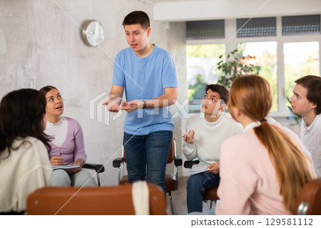 Young man teacher conducting lesson with group of students 129581112